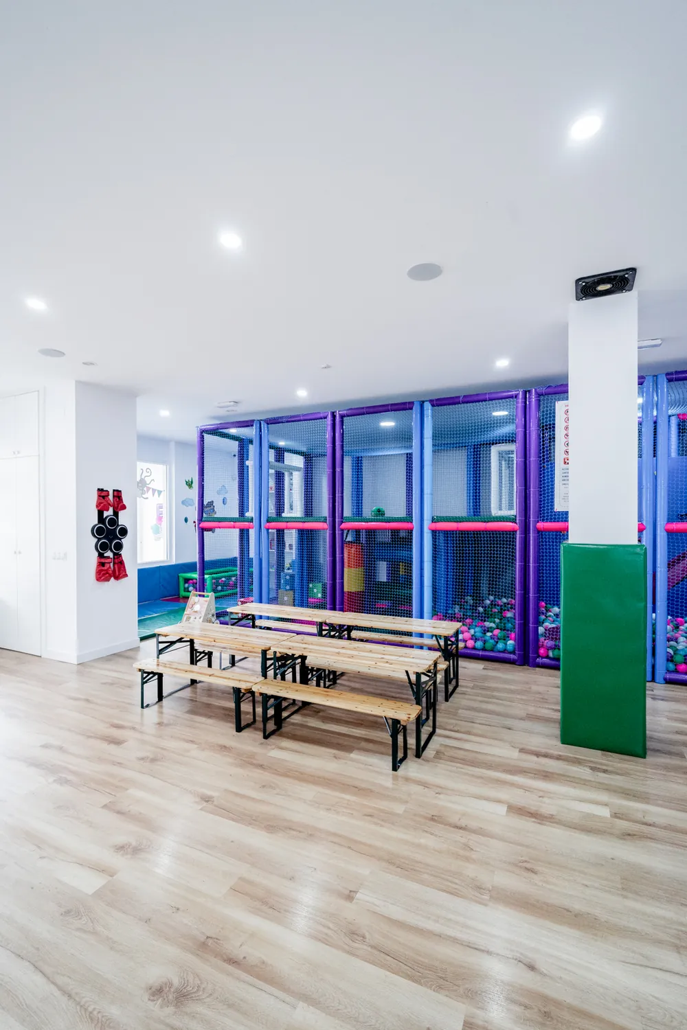 Sala de Espacio Loco con mesas para la merienda y el parque infantil al fondo